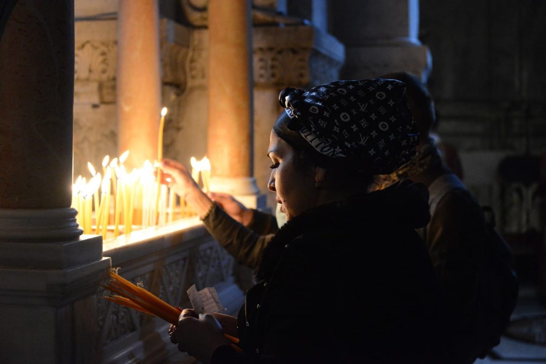 A woman Praying and litting candles near the Golgatha in the Easter procession ceremony in the church of the holy sepulchre in jersusalem