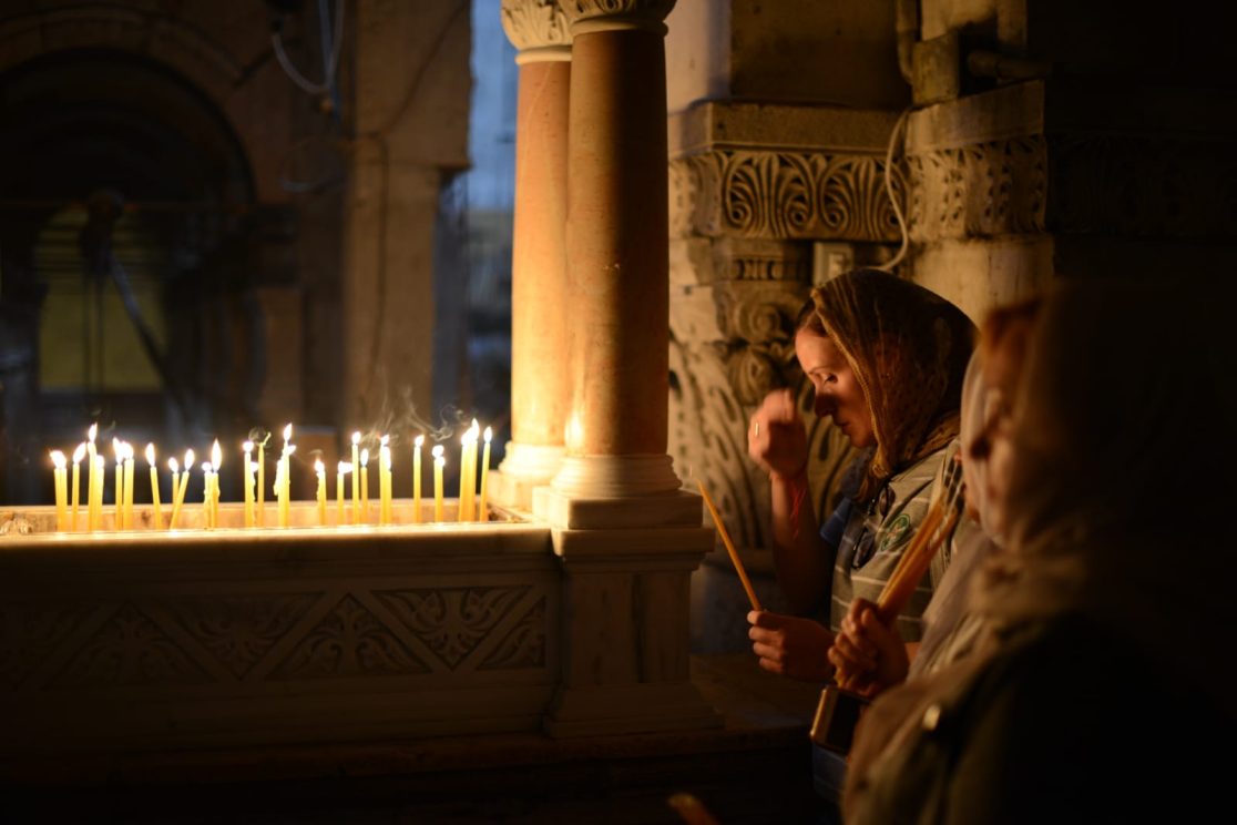 woman chrismas praying at the church of the holy sepulchre in Jerusalem with candles