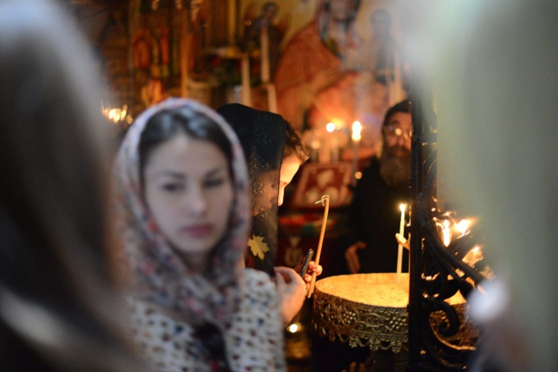 woman lighting a candle at the church of the holy sepulchre in Jerusalem